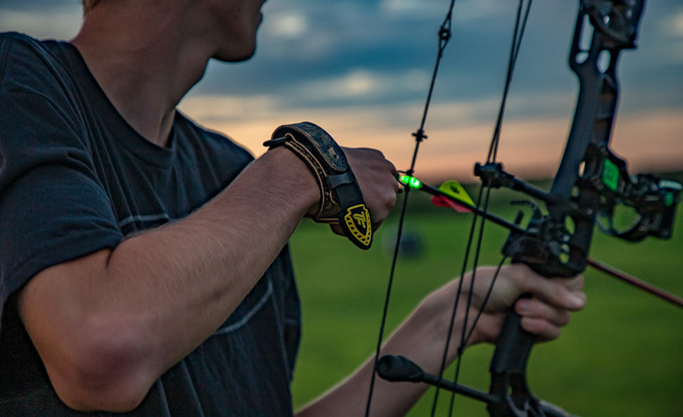 person holding knocked arrow with lighted green tip